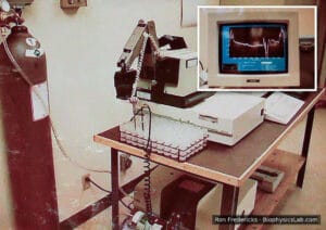 Eva-Scan FT-IR milk analyzer at Merced DHIA: a nitrogen cylinder, a robotic arm over sample trays and the FT-IR bench, with an inset of a monitor showing a milk spectrum.